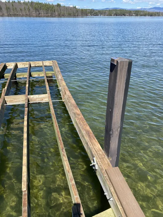 Exposed joists, cross-members and bolted connections beside a dark dock post