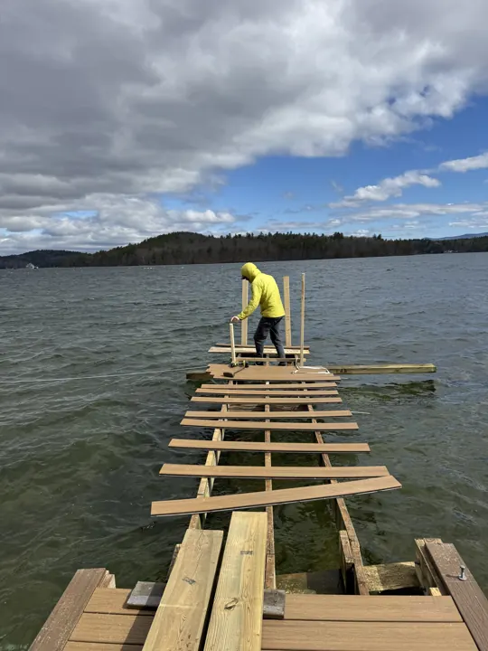 Worker laying out decking over exposed dock framing