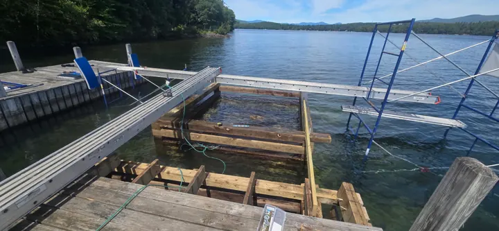 New timber crib framing visible through clear water beside the staging