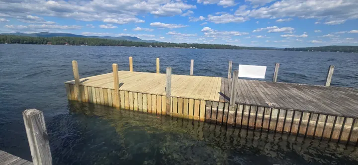 New timber deck and crib face beside the older dock, with blue lake water beyond