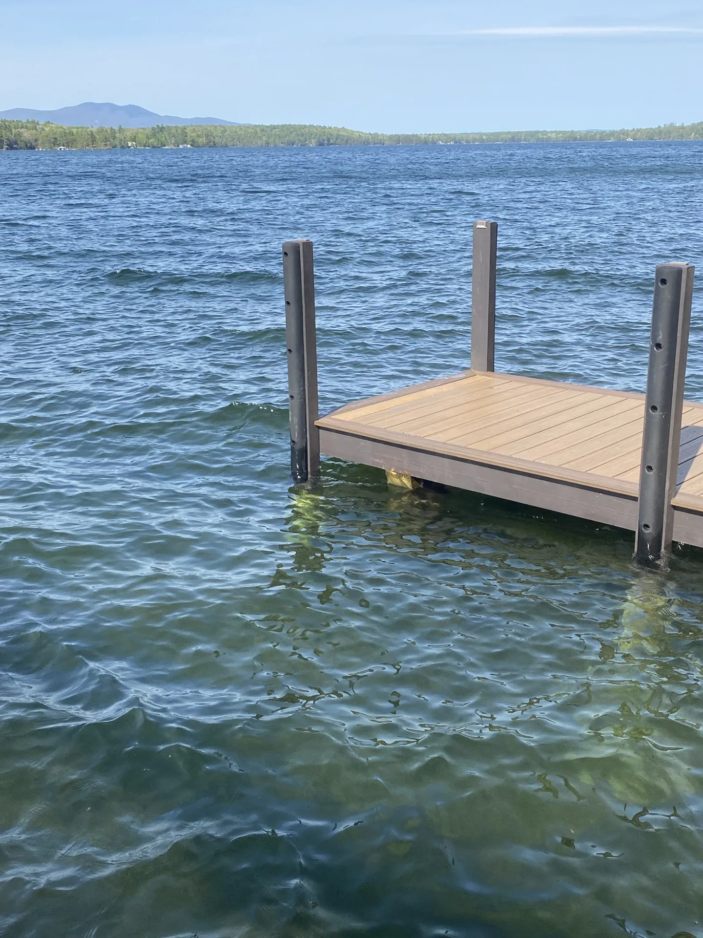 Finished composite dock with straight posts, blue lake water and wooded hills