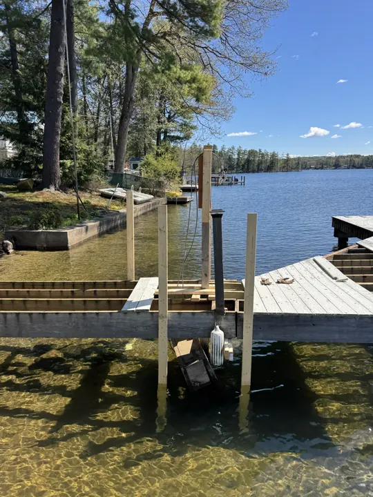 New timber uprights bolted beside the gray dock, with clear water below
