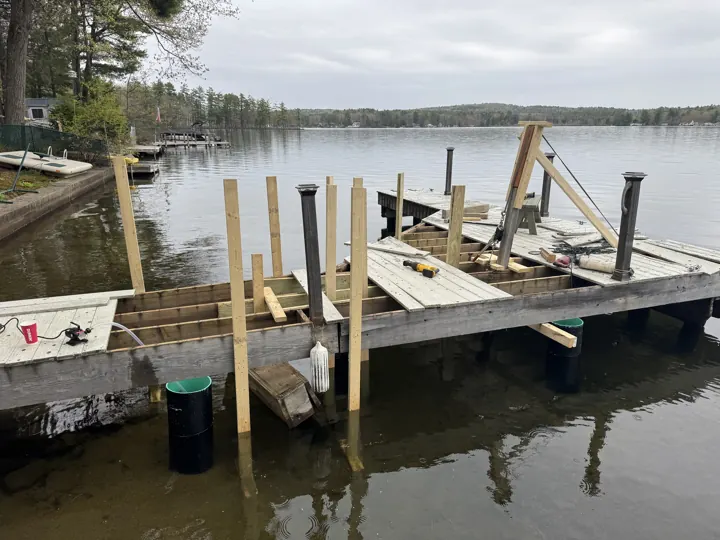 New posts and exposed framing on the gray dock during repair