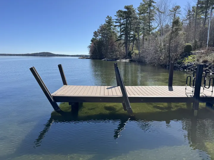 Brown dock with several posts leaning at different angles after winter