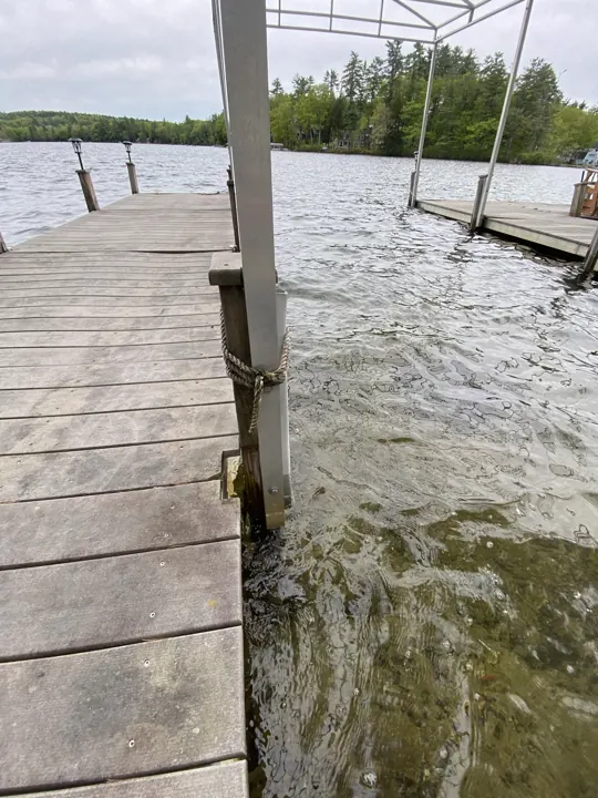 Boat lift post and mooring rope at the edge of the gray dock